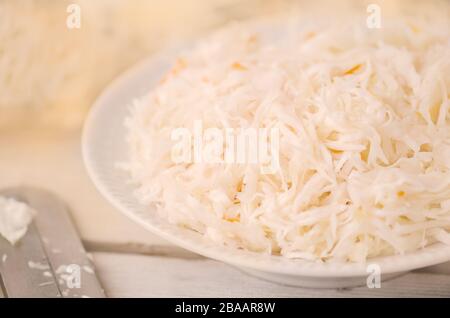 Kohlscheiben und Spezialschneider. Kohlkopf auf dem Tisch hacken. Kohlkopf auf Holzgrund gehopfft. Stockfoto