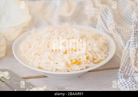 Kohlscheiben und Spezialschneider. Kohlkopf auf dem Tisch hacken. Kohlkopf auf Holzgrund gehopfft. Stockfoto