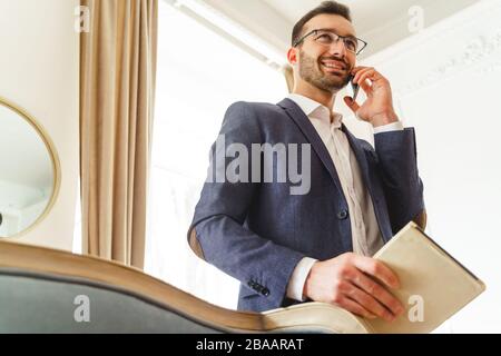 Mann mit einem Smartphone, das seinen Notizblock hält Stockfoto