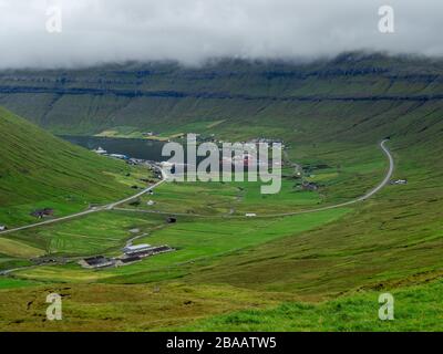 Färöer. Blick über das Dorf am Hang der Hügel. Bewölktes Wetter. Duftige Landschaft. Stockfoto