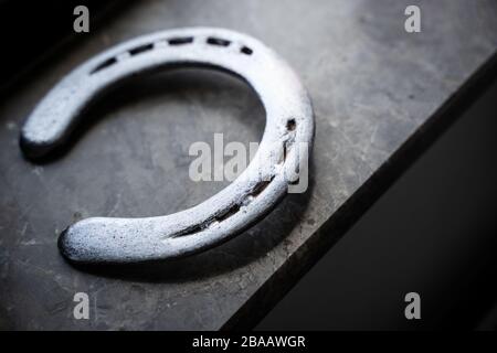 Draufsicht auf poliertes Hufeisen aus Stahl in natürlichem Licht auf einem Fensterschweller aus Marmor Stockfoto