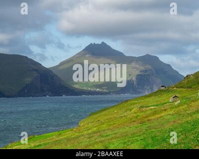 Färöer. Blick über die Bucht und die grünen Grashügel der Hügel. Duftige Landschaft. Stockfoto