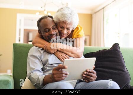 Älteres afroamerikanisches Paar kuscheln und benutzen Laptop in einer Kandare Stockfoto