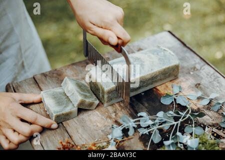 Frau macht handgefertigte Naturseifen auf einem alten Holztisch Stockfoto