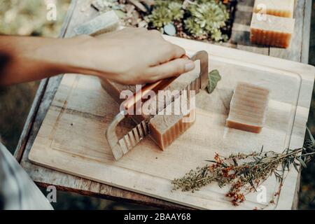 Frau macht handgefertigte Naturseifen auf einem alten Holztisch Stockfoto