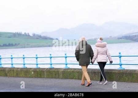 Älteres Paar spaziert täglich während des Regensturms in kalten Monaten auf der Meeresplanade Stockfoto