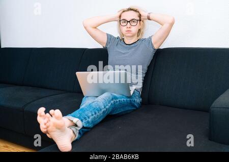 Online-Fernunterricht und -Arbeit. Weibliche Person, die im Büro arbeitet, arbeitet von zu Hause aus. Legere Frau mit Augengläser mit Laptop in Huis Stockfoto