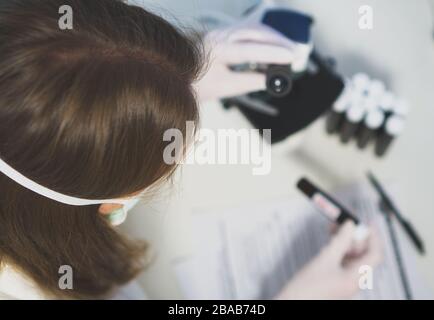 Wissenschaftler im Labor, der mit Mikroskop arbeitet. Covid-19-Konzept. Stockfoto