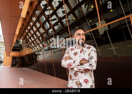 Bärtiger Mann mit gekreuzten Armen, während er gegen das Bürogebäude steht. Stockfoto