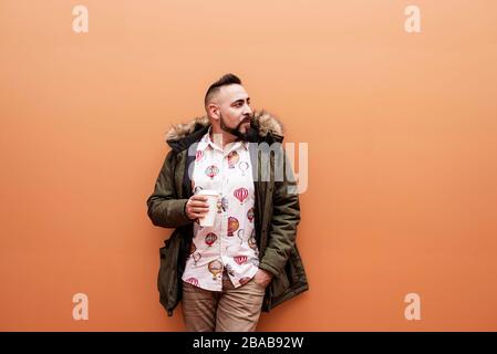 Gutaussehender Geschäftsmann, der im Freien mit einer Tasse Kaffee steht Stockfoto