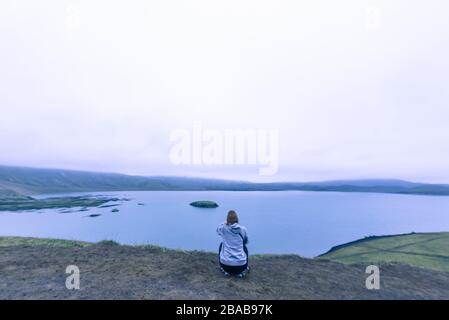 Frau sitzt, fotografiert den See im Hochland Island bei Sonnenuntergang Stockfoto