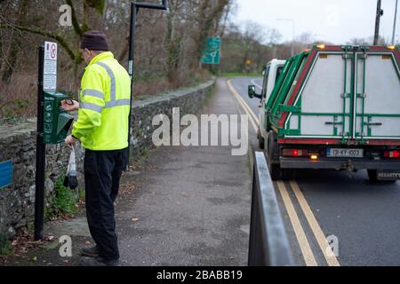 Ratsarbeiter beschäftigt bei der Arbeit Wartung Mutt Mitt Station für abbaubare Hund Abfallbeutel. Mutt Mitt Spender in Killarney, County Kerry, Irland Stockfoto