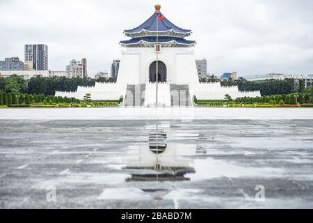 Atemberaubender Blick auf die Nationale Chiang Kai-Schek-Gedenkhalle in der Ferne mit ihrer Reflexion in einer Pfütze im Vordergrund. Stockfoto