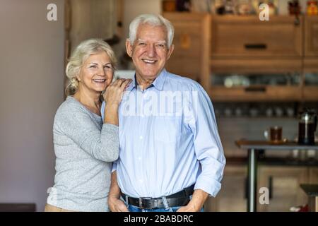 Glückliches älteres Paar, das sich in ihrem Haus umarmt Stockfoto