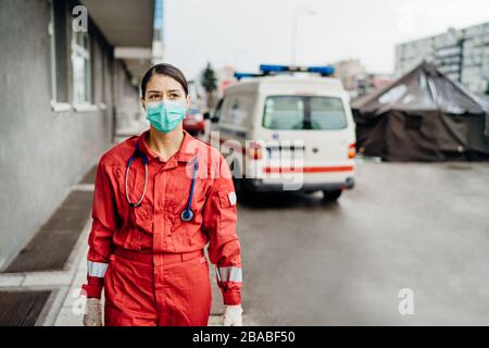 Trauriger überarbeiteter Sanitäter in Uniform vor der Isolationsanstalt.Notarzt in Angst und psychischem Stress,Kampfdruck Stockfoto