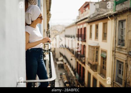 Junge europäische Frau, die Zeit für einen Kuraufenthalt zu Hause verbringen.Selbstversorgung,zu Hause bleiben.Blick auf den Balkon genießen.zu Hause entspannen.Zimmer mit Balkon Stockfoto