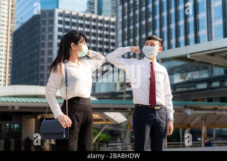 Ellenbogenschlag ist eine neue neue Begrüßung, um die Ausbreitung von Coronavirus zu vermeiden. Vor dem Bürogebäude treffen sich zwei asiatische Geschäftsfreunde. Statt Begrüßung Stockfoto
