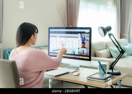Asiatische Geschäftsfrau spricht mit ihren Kollegen über Plan in der Videokonferenz. Multiethnisches Business Team, das Computer für ein Online-Meeting in Video verwendet Stockfoto