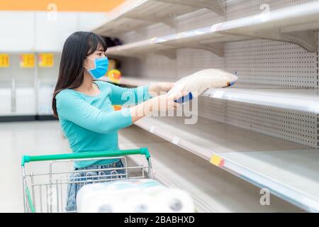 Asian Woman holt letzte Reispackung im Supermarkt leere Regale inmitten der COVID-19-Coronavirus Ängste, Käufer panieren den Kauf und die Lagerung von toilettenpapier pr Stockfoto