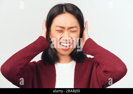 Schreckliche Frau verstopft Ohren mit Handflächen, schließt Augen Stockfoto