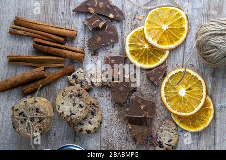 Getrocknete Orangen, Schokoladenscheiben, Schokoladengebäcke und Zimt auf einem Holztisch Stockfoto