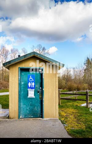 Surrey, Kanada - 25. März 2020: Toilette im Freien im Tynehead Regional Park in Metro Vancouver mit Informationen zum Gesundheitszustand des Corona-Virus vor der Tür Stockfoto