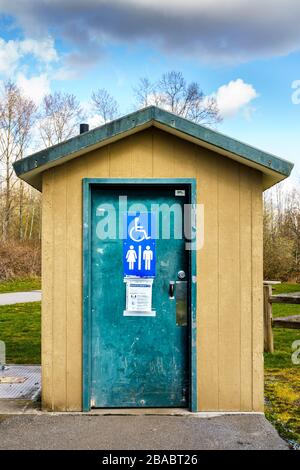 Surrey, Kanada - 25. März 2020: Toilette im Freien im Tynehead Regional Park in Metro Vancouver mit Informationen zum Gesundheitszustand des Corona-Virus vor der Tür Stockfoto