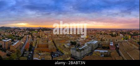 Luftaufnahme des Stadtzentrums von Cesena mit mittelalterlichen Gebäuden während des Sonnenuntergangs mit violettem, orangefarbenem, rotem, gelbem Himmel Stockfoto