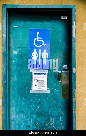 Surrey, Kanada - 25. März 2020: Toilette im Freien im Tynehead Regional Park in Metro Vancouver mit Informationen zum Gesundheitszustand des Corona-Virus vor der Tür Stockfoto