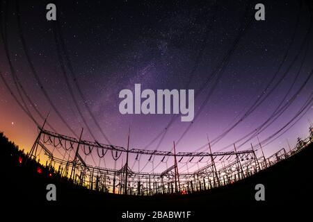 Hochspannungstürme in der Nacht und der Milchstraße Stockfoto