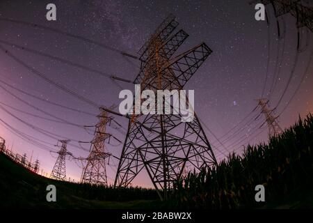 Hochspannungstürme in der Nacht und der Milchstraße Stockfoto