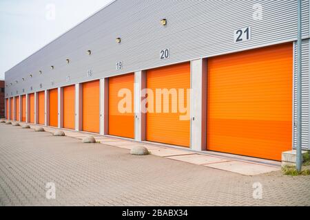 außen eine gewerbliche Lagerhalle mit orange Rolltore Stockfoto