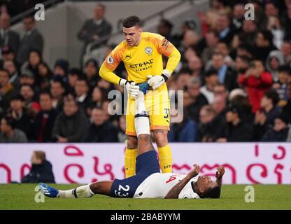 Steven Bergwijn von Tottenham Hotspur wird vom Manchester City Torhüter Ederson während des Premier-League-Spiels im Tottenham Hotspur Stadium, London, gegen Krampf behandelt. Stockfoto