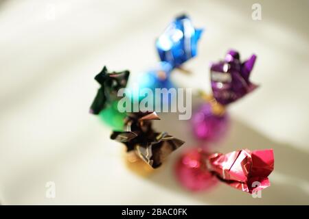 Pralinen in bunten bunten bunten, farbenfrohen Hüllen auf einem sonnigen Tisch, Draufsicht, selektiver Fokus. Stockfoto
