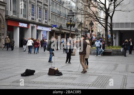 Spaziergänger kommen an einem Straßenspieler vorbei, der auf der Hauptpromenade von Belgrad Geige spielt. Stockfoto