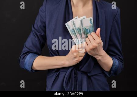 Mädchen in einer Jacke entfernt rumende Banknoten in einer Jacke auf schwarzem Hintergrund. Nahaufnahme. Stockfoto