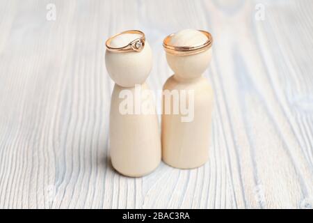Hochzeit klingelt auf abstrakten Figuren von Mann und Frau auf Holzhintergrund. Nahaufnahme. Stockfoto