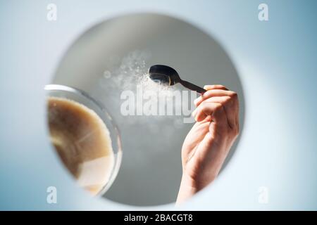 Mann, der dem Kaffee Zucker zufügt, von innen BETRACHTET EINE Tasse Stockfoto