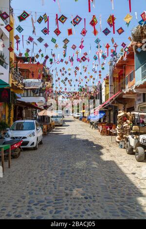 Der bunte Ojo de dios streunte über eine Kopfsteinpflasterstraße in der Stadt Sayulita, Mexiko, Nayarit. Stockfoto