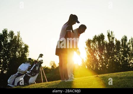 Die jungen Frauen und Senioren spielen Golf Stockfoto