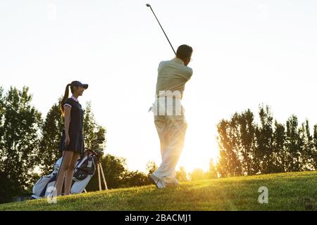 Die jungen Frauen und Senioren spielen Golf Stockfoto