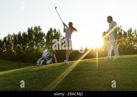 Die jungen Frauen und Senioren spielen Golf Stockfoto