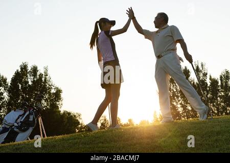 Die jungen Frauen und Senioren spielen Golf Stockfoto