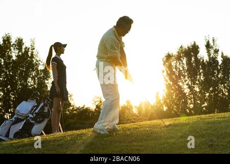 Die jungen Frauen und Senioren spielen Golf Stockfoto