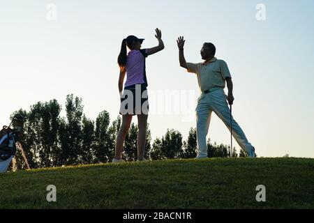 Die jungen Frauen und Senioren spielen Golf Stockfoto