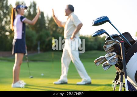 Die jungen Frauen und Senioren spielen Golf Stockfoto
