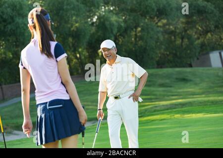 Die jungen Frauen und Senioren spielen Golf Stockfoto