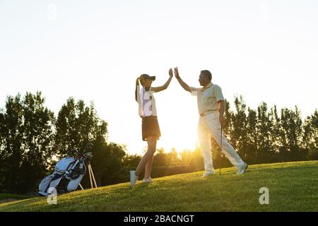 Die jungen Frauen und Senioren spielen Golf Stockfoto