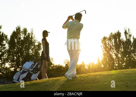 Die jungen Frauen und Senioren spielen Golf Stockfoto