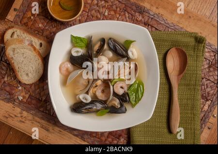 Fischeintopf, ähnlich wie Bouillabaisse, mit einer Vielzahl von Meeresfrüchten wie Muscheln, Muscheln, Garnelen, Calamari in einer Fischfond Basis garniert mit Basilikum Stockfoto